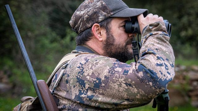 Un cazador mira por los prismáticos.