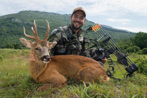 Un cazador posa con un corzo.