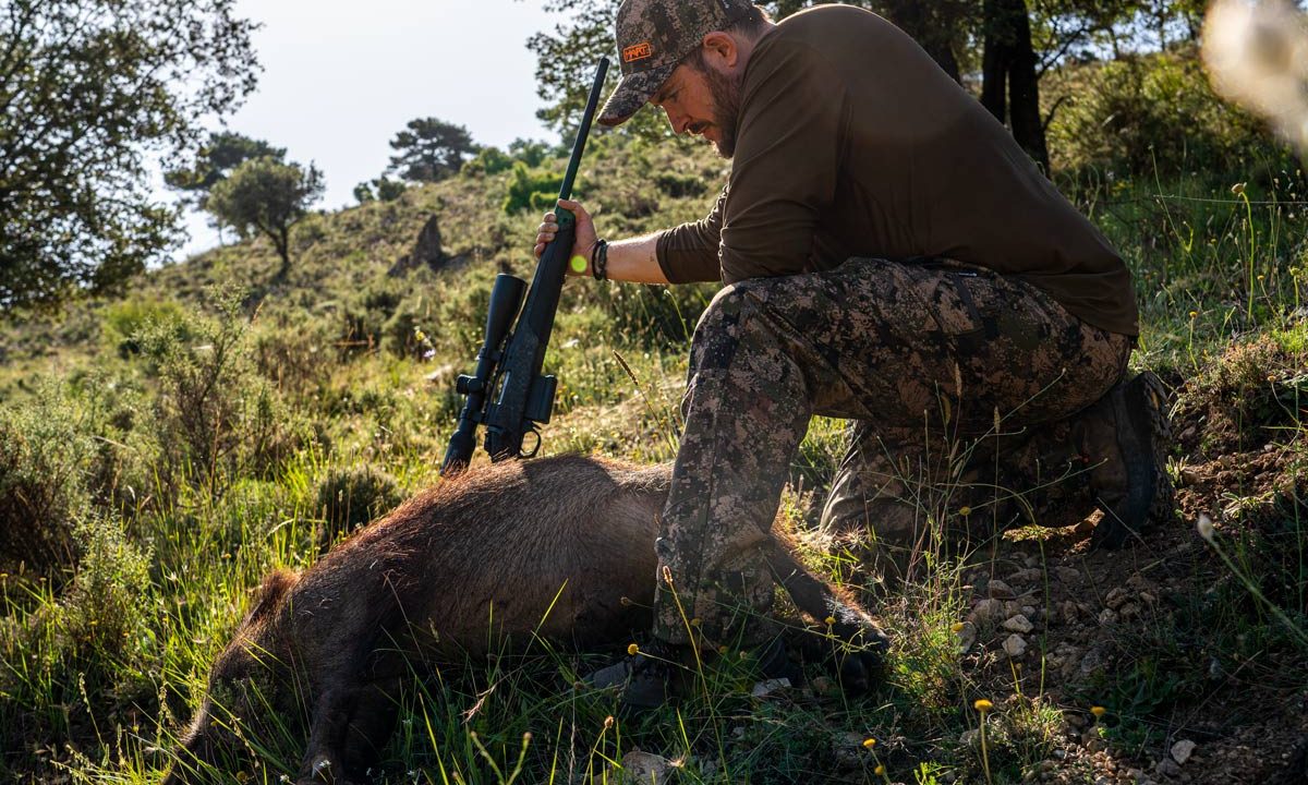Un cazador con un jabalí abatido.