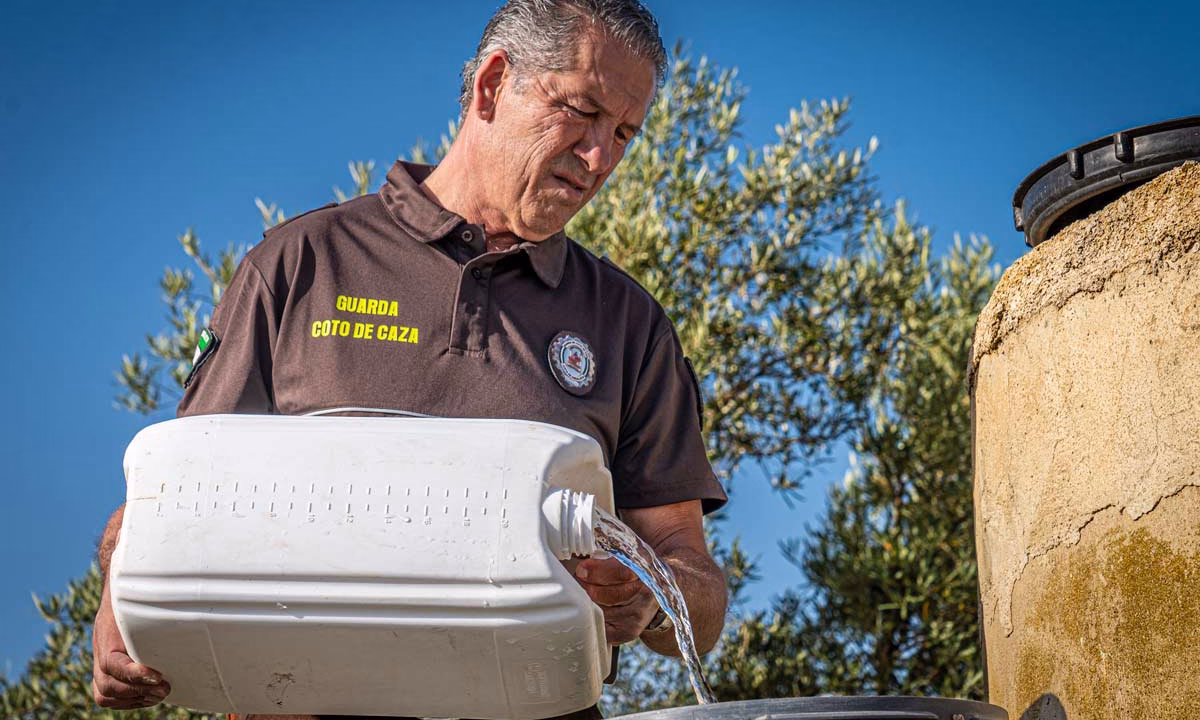Un guarda de coto de caza andaluz rellena un bidón de agua.