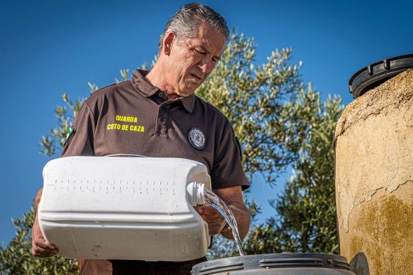 Un guarda de coto de caza andaluz rellena un bidón de agua.