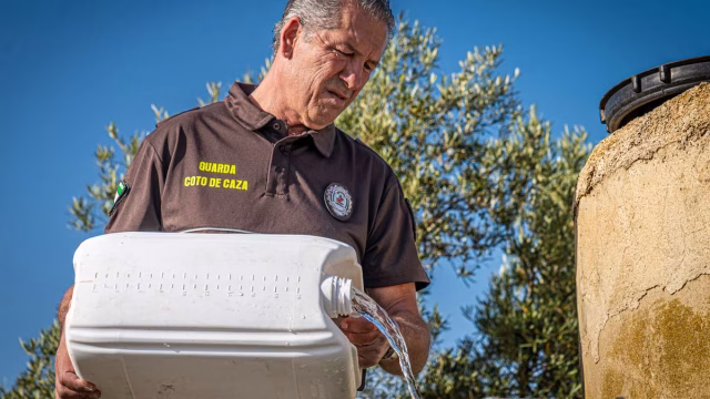 Un guarda de coto de caza andaluz rellena un bidón de agua.